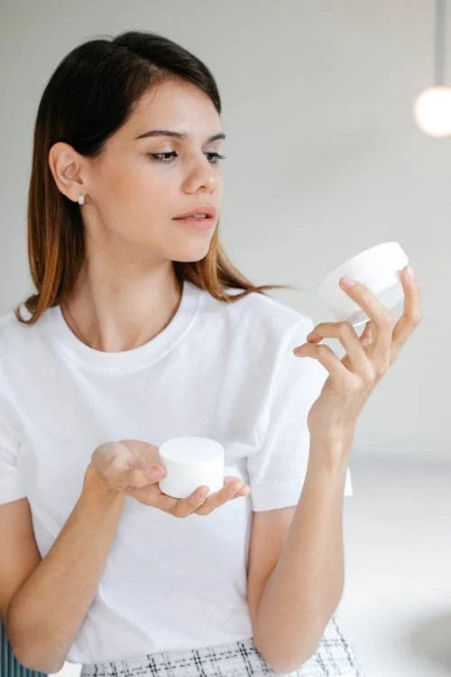 Foto di una donna che sta guardando una crema viso