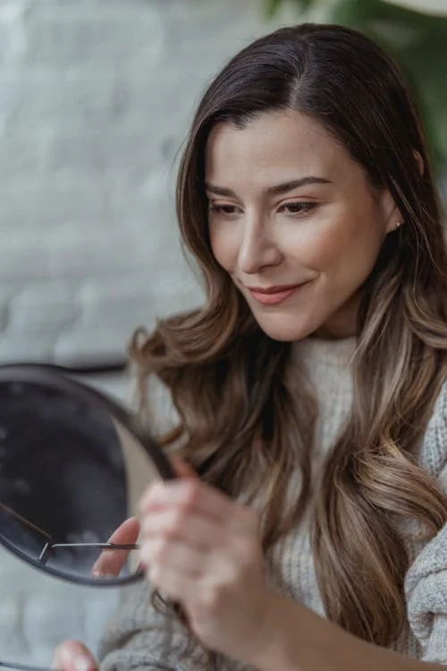 Foto di una donna che si guarda allo specchio e sorride