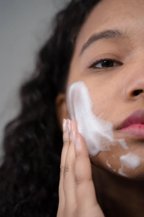 Foto di una donna con della schiuma in faccia per lavarsi il viso