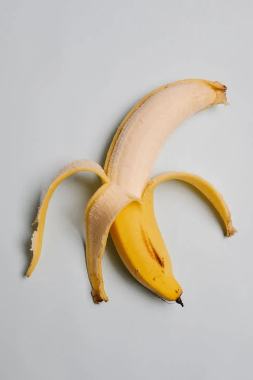 Foto di una banana sbucciata per metà su sfondo bianco