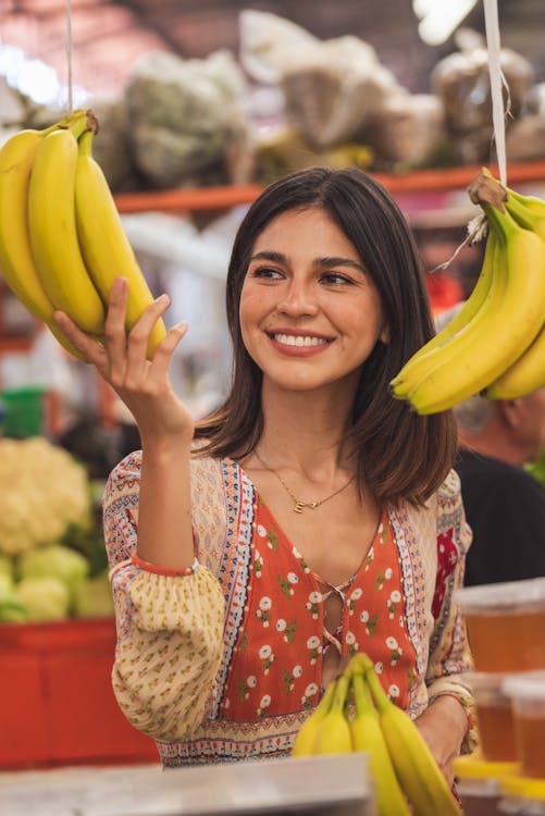 Foto di una ragazza che sorride mentre tocca delle banane