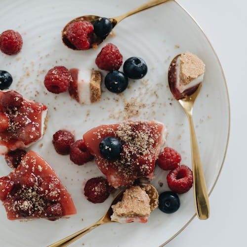 Foto di più pezzi di torta cheesecake ai frutti rossi tagliata e presa con dei cucchiaini