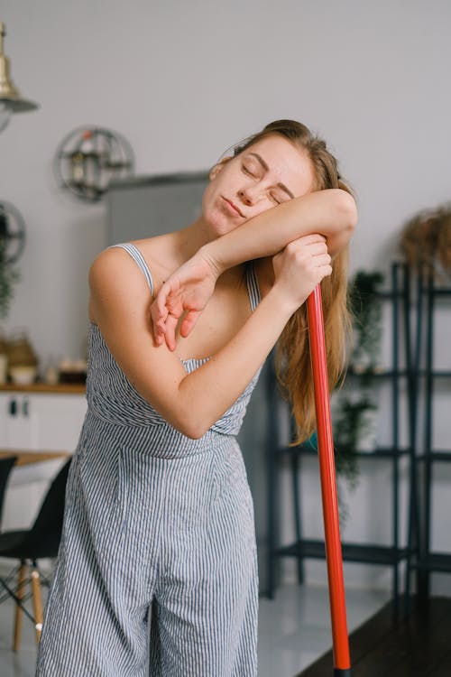 Foto di una ragazza in piedi dormiente sul manico di una scopa