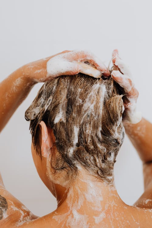 Foto di una donna di spalle mentre si lava i capelli