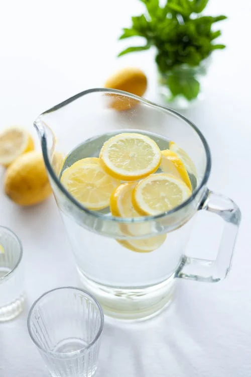 Foto di una brocca di vetro contenente acqua e dei limoni tagliati dentro